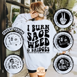 May include: White sweatshirt with black text that reads "I burn sage weed & bridges" and "Whatever keeps the negativity away".  Four black and white circular designs with the text "Whatever keeps the negativity away" are on the sweatshirt and show a joint, a lit stick of dynamite, a skeleton with a peace sign, and a skeleton with a joint.