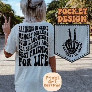 May include: White t-shirt with black text that reads "Partners in Crime Memory Makers Loud Laughters Tea Spillers and Best Friends For Life". A pocket on the shirt features a black skeleton hand making a peace sign with the text "Partners in Crime" around it.