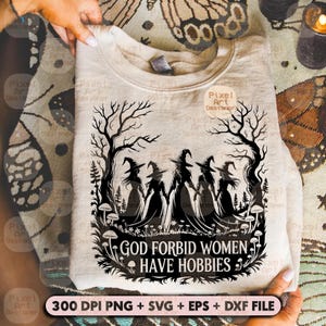 May include: A light beige sweatshirt with a black graphic of five witches holding hands under bare trees. The text "GOD FORBID WOMEN HAVE HOBBIES" is below the witches. The bottom of the image includes the text "300 DPI PNG + SVG + EPS + DXF FILE".