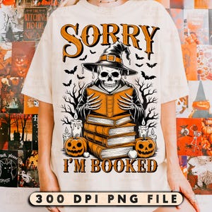 Peut inclure: T-shirt crème avec un motif d'Halloween. Le design présente un squelette portant un chapeau de sorcière et lisant un livre, avec l'inscription "SORRY I'M BOOKED". Des chauves-souris, des citrouilles et des bougies complètent le motif.