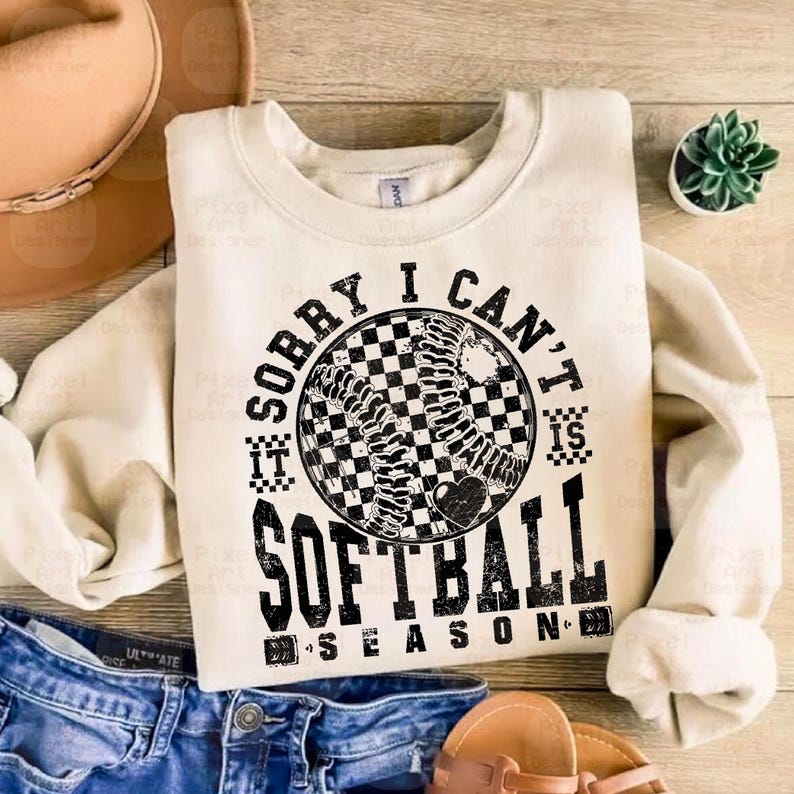 May include: A cream-colored sweatshirt with the text "Sorry I can't it's softball season" in black with a black and white checkered softball graphic.