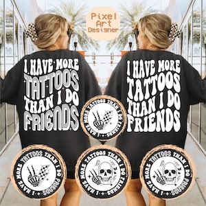 May include: Two black sweatshirts with white text that reads "I have more tattoos than I do friends".  Each sweatshirt has a circular design on the front with a skull and crossbones and the text "I have more tattoos than I do friends".