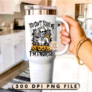 May include: White insulated tumbler with a handle, featuring a Halloween-themed design. The design includes a skeleton in a nurse's uniform, pumpkins, and the text "YOU CAN'T SCARE ME I'M A NURSE". The tumbler also has a clear lid and a straw.