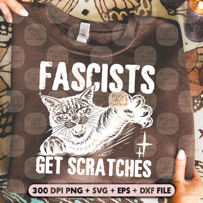May include: A brown sweatshirt with the text "FASCISTS GET SCRATCHES" and a graphic of a cat clawing. The design is in white. The bottom of the sweatshirt has the text "300 DPI PNG + SVG + EPS + DXF FILE".