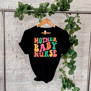 K&ouml;nnte beinhalten: Schwarzes T-Shirt mit dem Text "MOTHER BABY NURSE" in Regenbogenfarben.