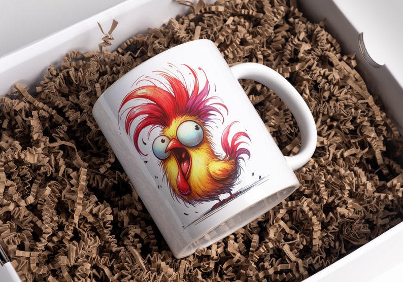 May include: White ceramic mug featuring a cartoon rooster with vibrant red, yellow, and orange feathers and an exaggerated expression. The mug is inside a white box filled with brown crinkle paper.