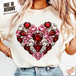 May include: A cream-coloured t-shirt with a large heart design made of red, pink, and clear gemstones. The heart is centrally placed and detailed with various shapes and sizes of gems. Text at the top left reads "FREE 10 DESIGNS INCLUDED".