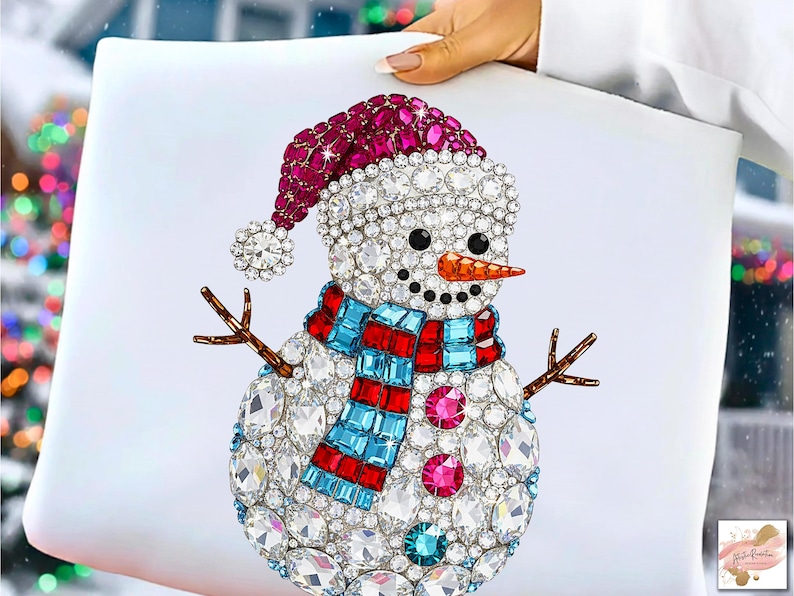 Puede incluir: Un dise&ntilde;o decorativo de mu&ntilde;eco de nieve con un gorro rojo y blanco, una bufanda azul y roja y una nariz de zanahoria. El mu&ntilde;eco de nieve est&aacute; adornado con cristales transparentes y rosas y tiene brazos de ramitas. El dise&ntilde;o est&aacute; sobre un fondo blanco.