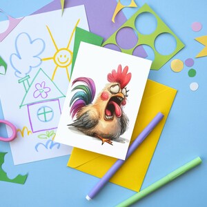 May include: A greeting card featuring a cartoon rooster with a wide open mouth, red comb, and glasses. The card is on a yellow envelope, with a drawing of a house and sun, scissors, and colorful paper cutouts on a blue background.