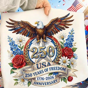 以下が含まれることがあります： 鷲のイラストと「250 Years of Freedom」と「1776-2026 Anniversary」の文字が入った愛国的なデザイン。赤、白、青の色使いで、花柄とバナーが特徴です。