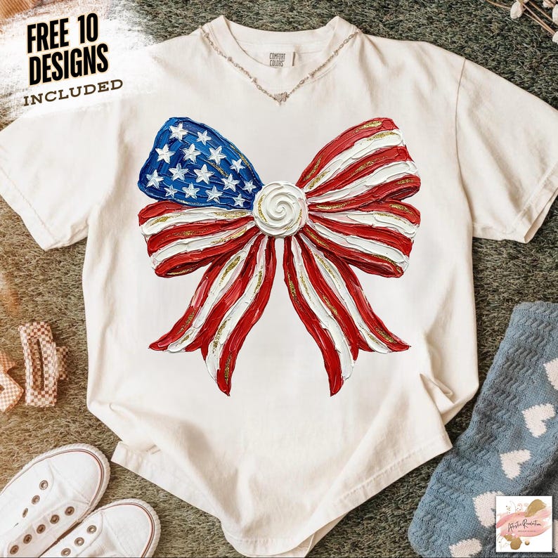 K&ouml;nnte beinhalten: Ein wei&szlig;es T-Shirt mit einem gro&szlig;en Schleifendesign in Rot, Wei&szlig; und Blau, das an die amerikanische Flagge erinnert. Der Bogen hat ein strukturiertes Aussehen mit goldenen Akzenten. Der Text "FREE 10 DESIGNS INCLUDED" ist oben links aufgedruckt.