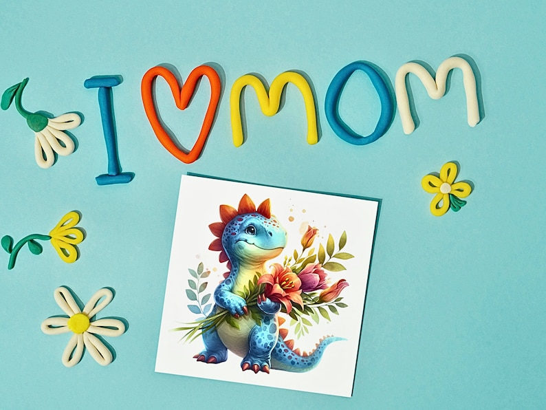 Puede incluir: Una tarjeta con un dinosaurio azul sosteniendo un ramo de flores. La tarjeta est&aacute; rodeada de letras de plastilina de colores que deletrean "I love mom".