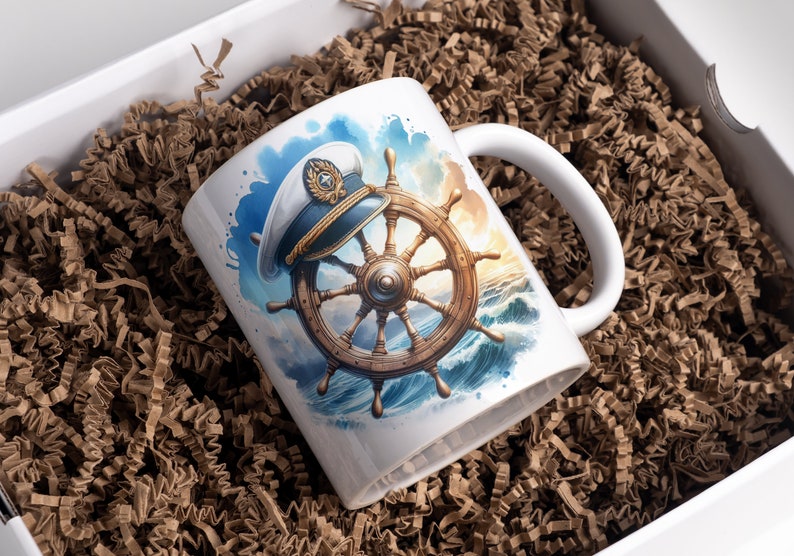 May include: White ceramic mug featuring a nautical design. The artwork depicts a ship's wheel and captain's hat against a backdrop of ocean waves and a sunset. The mug is presented in a white gift box with brown paper filler.