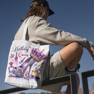 May include: White tote bag with a colorful design featuring a high-heeled shoe, a crown, and makeup. The text "Birthday Queen" is printed on the bag.