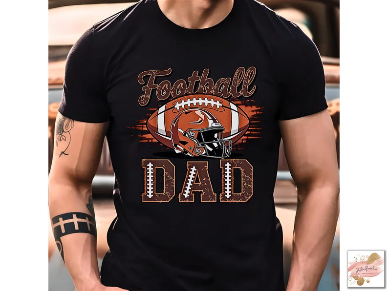 May include: Black t-shirt featuring a football design. The design includes a brown football, a helmet, and the word "Football" in a script font above the football. Below the football is the word "DAD".