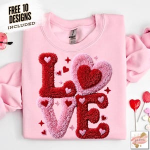May include: A light pink sweatshirt with the word "LOVE" embroidered in red and pink textured fabric. The design includes heart shapes and stars. Text at the top left reads "FREE 10 DESIGNS INCLUDED".