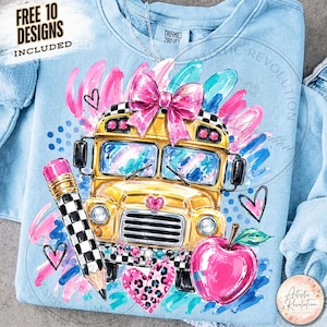 May include: A light blue sweatshirt featuring a graphic of a yellow school bus with a large pink bow, a black and white checkered pencil, and a pink apple. The design includes colorful brushstrokes, heart shapes, and the text FREE 10 DESIGNS INCLUDED.