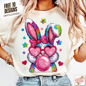 May include: Cream-colored sweatshirt featuring a colorful bunny design. The bunny wears heart-shaped sunglasses and blows a bubble. The design includes stars and hearts. Text at the top left reads "FREE 10 DESIGNS INCLUDED".