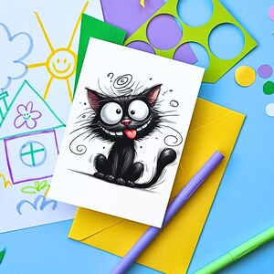 K&ouml;nnte beinhalten: Eine wei&szlig;e Karte mit einer schwarz-wei&szlig;en Cartoon-Illustration einer Katze mit herausgestreckter roter Zunge. Die Katze hat einen Wirbel auf dem Kopf und ist von schwarzen Wirbeln umgeben. Die Karte liegt auf einem gelben Umschlag mit einem lila Stift und einem gr&uuml;nen Stift.