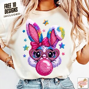May include: Cream-colored sweatshirt featuring a colorful bunny design with heart-shaped glasses blowing a bubblegum bubble. The bunny has a pink bow and is surrounded by star accents. Text at the top left reads "FREE 10 DESIGNS INCLUDED."