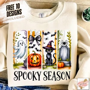May include: Cream-colored sweatshirt with a Halloween-themed graphic. The design includes a ghost, jack-o'-lantern, black cat, spider, tombstone, and the words "Spooky Season". The text "Free 10 Designs Included" is also visible.
