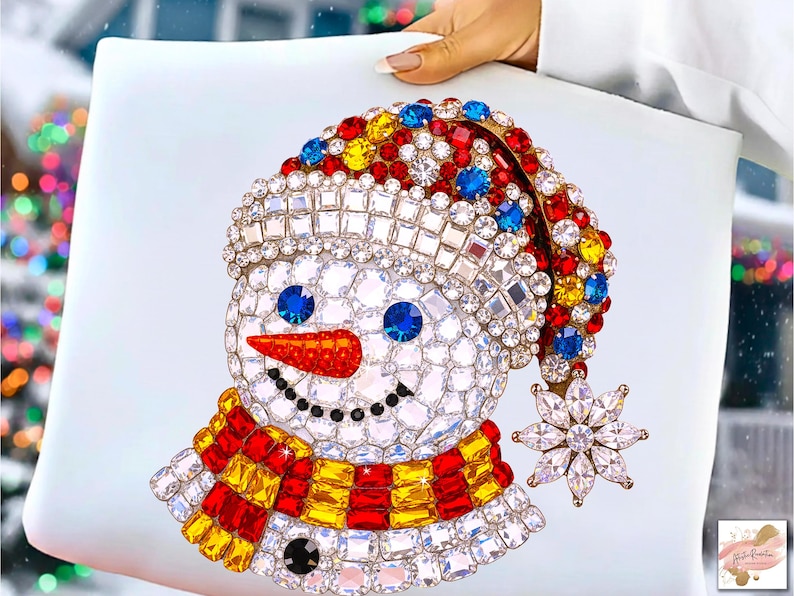 Puede incluir: Un dise&ntilde;o decorativo de mu&ntilde;eco de nieve con sombrero, bufanda y un copo de nieve de colores. El mu&ntilde;eco de nieve est&aacute; adornado con cristales brillantes en varios colores, incluyendo rojo, amarillo, azul y transparente. El dise&ntilde;o est&aacute; sobre un fondo blanco.