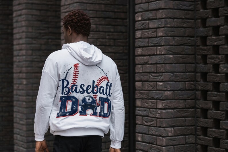 May include: White hooded sweatshirt with a baseball graphic and the text "Baseball Dad" printed on the back.