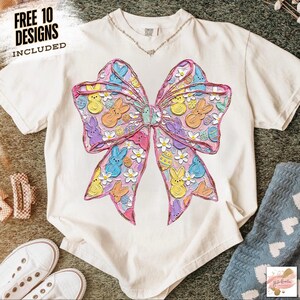 May include: Cream-colored t-shirt featuring a large, colorful bow design with Easter-themed elements. The bow is filled with bunnies, chicks, and Easter eggs in pastel colors. The text "FREE 10 DESIGNS INCLUDED" is in the upper left corner.