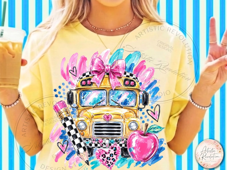 May include: A pale yellow t-shirt featuring a graphic print of a yellow school bus with a large pink bow on top, a black and white checkered pencil, a bright pink apple, and various pink and blue abstract brushstrokes and heart shapes.