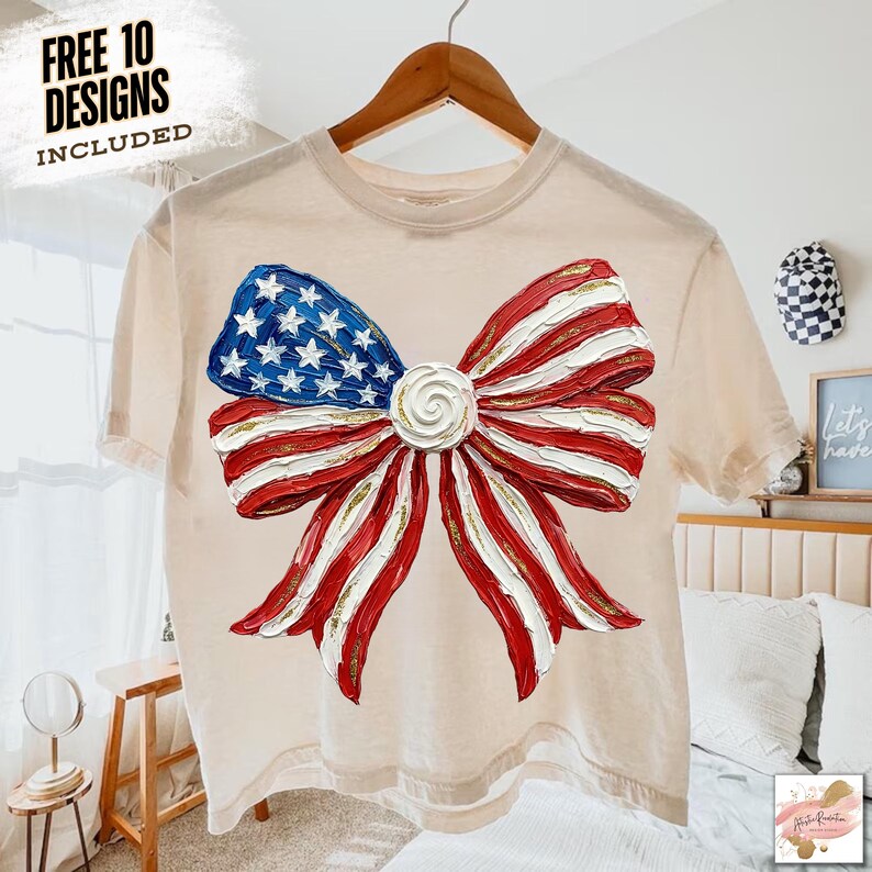 K&ouml;nnte beinhalten: Beiges T-Shirt mit einem gro&szlig;en Schleifendesign in Rot, Wei&szlig; und Blau, das an die amerikanische Flagge erinnert. Der Bogen hat ein strukturiertes Aussehen mit goldenen Akzenten. Der Text "FREE 10 DESIGNS INCLUDED" ist links oben aufgedruckt.