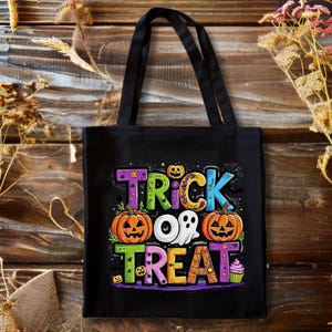 May include: A black tote bag featuring a colorful graphic with the text TRICK OR TREAT. The design includes two orange jack-o'-lanterns, a white ghost, a small cupcake, and various small bats and stars in shades of purple, blue, and yellow.