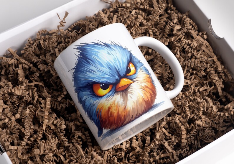 May include: White ceramic mug with a colorful cartoon illustration of a blue bird with an angry expression. The bird has yellow eyes, an orange beak, and orange and brown feathers.