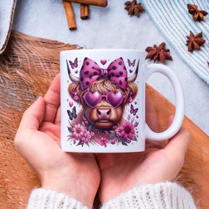 May include: White ceramic mug with a pink and black illustration of a Highland cow wearing pink sunglasses and a pink polka dot bow. The cow is surrounded by pink flowers.