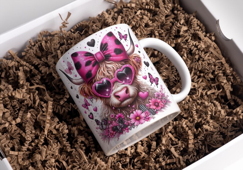 May include: White ceramic mug with a pink and black cow wearing pink heart-shaped sunglasses and a pink and black polka dot bow. The mug is surrounded by pink flowers and butterflies.