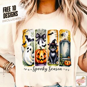 May include: Cream-colored t-shirt featuring a Halloween-themed design. The design includes a ghost, pumpkin, black cat, and tombstone, with the words "Spooky Season" and "Free 10 Designs Included".