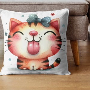 Pode incluir: Uma almofada branca com uma ilustra&ccedil;&atilde;o de desenho animado fofa de um gato tigrado vermelho e laranja com um la&ccedil;o azul. O gato est&aacute; mostrando a l&iacute;ngua e tem uma express&atilde;o feliz.