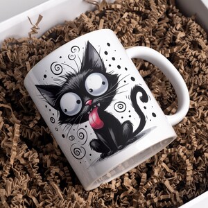 Pode incluir: Caneca de cer&acirc;mica branca com uma ilustra&ccedil;&atilde;o de um gato preto. O gato tem olhos grandes e redondos, uma l&iacute;ngua longa que se projeta e uma cauda preta. O fundo &eacute; branco com redemoinhos e pontos pretos.