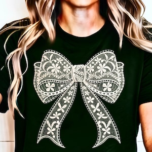 Puede incluir: Una camiseta negra con un dise&ntilde;o de lazo de encaje blanco. El lazo es intrincado y detallado, con un delicado patr&oacute;n floral.