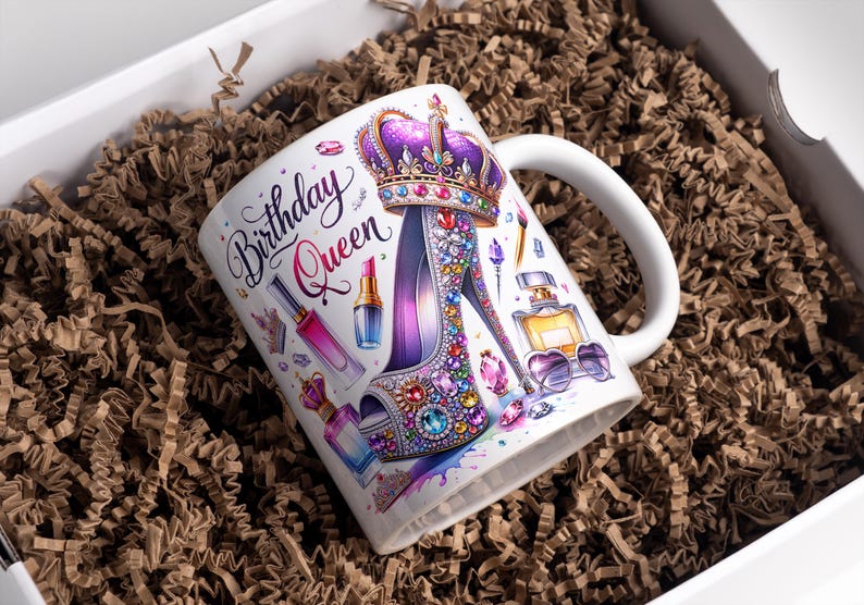 May include: White ceramic mug with a colorful design featuring a high-heeled shoe adorned with jewels, a crown, and makeup items. The text "Birthday Queen" is written in a decorative font.