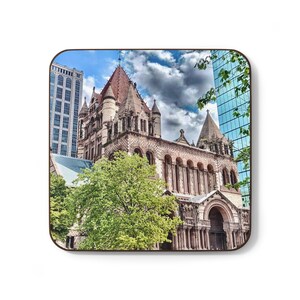 May include: Square coaster featuring a detailed image of a historic church with a red-tiled roof and ornate architecture. The image includes a blue sky with clouds and modern buildings. The coaster is a decorative item.
