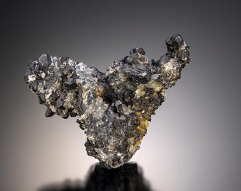Może przedstawiać: Gromada czarnych i srebrnych metalicznych kryształów mineralnych o szorstkiej, fakturowanej powierzchni.