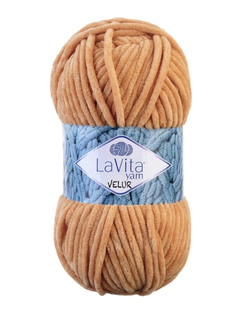 May include: A ball of tan-colored LaVita Velur yarn. The yarn is wrapped with a light blue band featuring the brand's logo. The yarn appears soft and plush, ideal for knitting or crocheting projects. The label indicates it is "Velur" yarn.