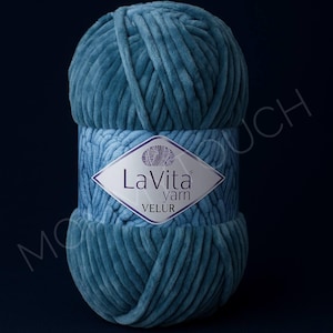 May include: A ball of teal-colored La Vita Velur yarn. The yarn is wrapped with a label that reads "La Vita yarn VELUR". The yarn has a soft, velvety texture, perfect for knitting or crocheting projects.