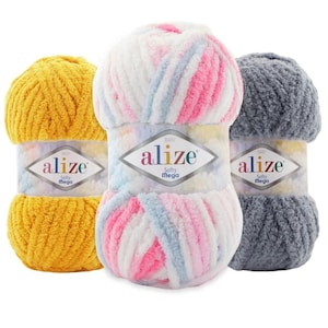 Puede incluir: Tres ovillos de hilo en diferentes colores. El hilo es suave y esponjoso y está etiquetado como "Alize Softy Mega". Los colores son amarillo, rosa y azul a rayas y gris.