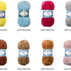 May include: A collection of eight skeins of Lavita Velur yarn in various colors, including yellow, blue, red, gray, brown, and pink. Each skein is labeled with the Lavita brand and a unique product code. The yarn has a soft, velvety texture.