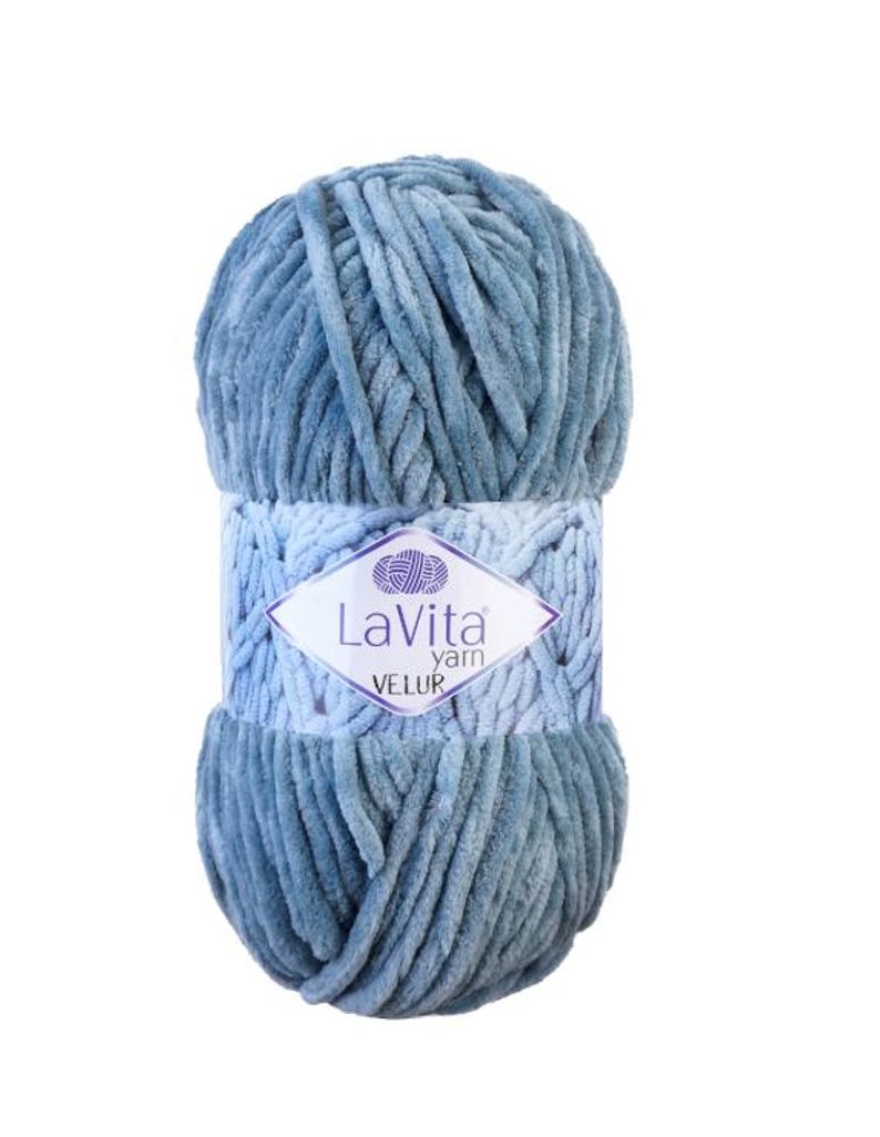May include: A ball of blue-grey LaVita Velur yarn. The yarn is soft and plush, with a velvety texture. The label features the brand name and the word "VELUR" in a diamond shape.