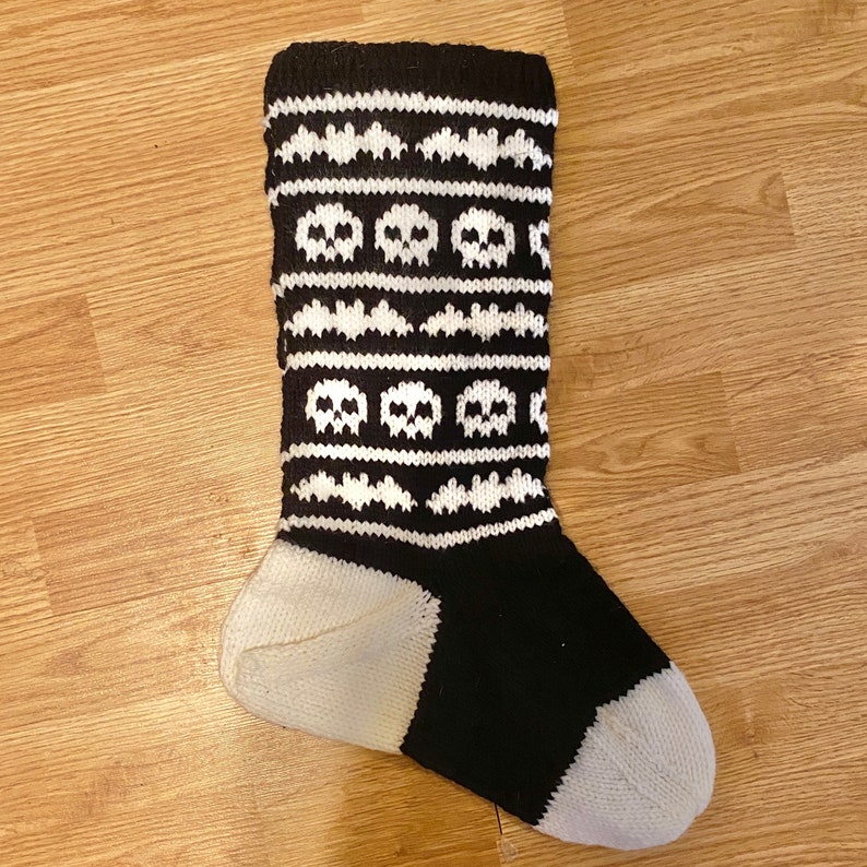 May include: Black and white knitted sock with a skull and bat pattern.