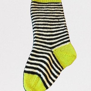 May include: A black and white striped sock with a bright yellow cuff. The sock is knitted and has a ribbed texture.