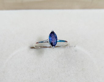 Può includere: Un anello d'argento con una pietra preziosa blu scuro a forma di marquise.
