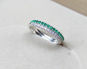 Könnte beinhalten: Ein Silberring mit einer doppelten Reihe von Edelsteinen. Die obere Reihe besteht aus grünen Smaragden und die untere Reihe aus klaren Diamanten.